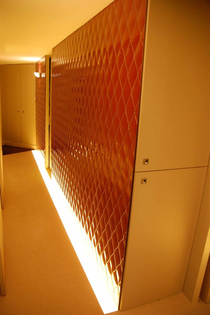 Beautiful textured ceramic wall tiles installed in a narrow hallway with a warm white cold cathode floor lighr edge