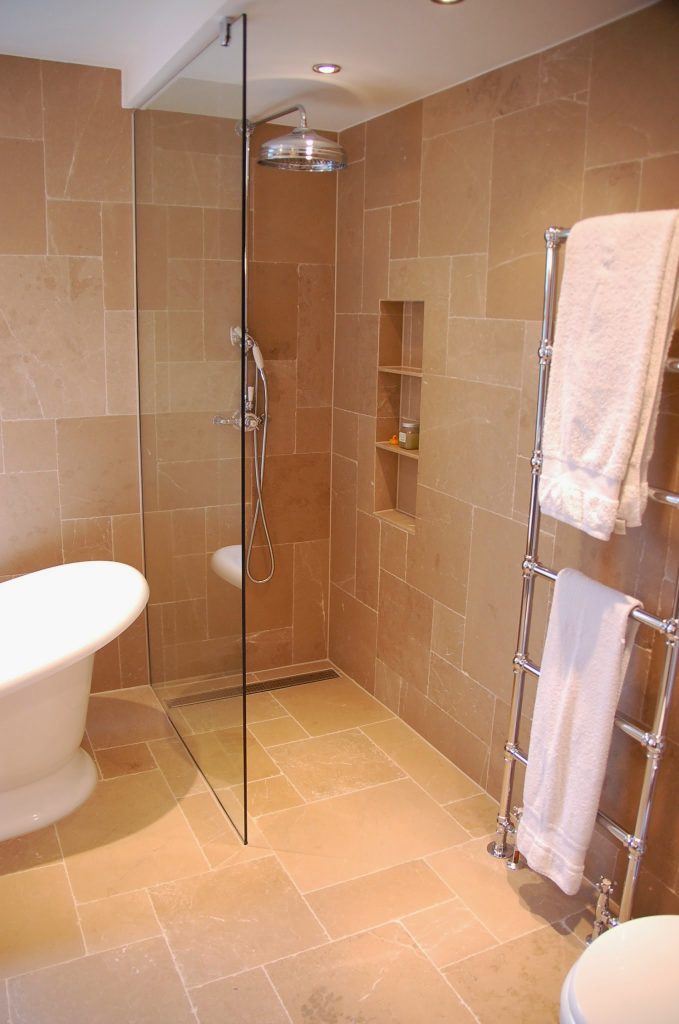 Limestone bathroom in opus romano pattern, sloped tiled flooring to the drain with traditional bathroom features